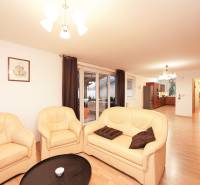 Családi ház nappalija krémszínű kanapéval és fa mintázatú padlóval.