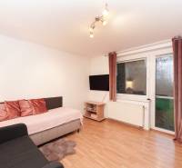 Nappali egy családi házban kanapéval, televízióval és fa dekorációjú padlóval.