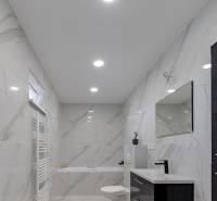 Fürdőszoba egy családi házban kerámia falakkal és káddal, fekete mosdóval és tükörrel.