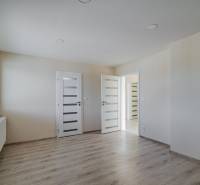 Szoba egy családi házban fa dekorációjú padlóval, világos falakkal és ablakkal.