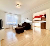 Nappali egy kétszobás lakásban barna kanapéval és fa dekorációjú padlóval.