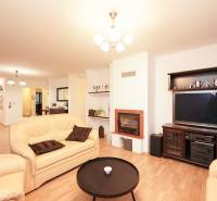 Nappali családi házban kandallóval, bőr kanapékkal és fa mintázatú padlóval.