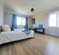 Szoba ággyal, két ablakkal, zongorával és fa dekorációjú padlóval egy családi házban.