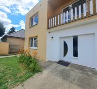 Családi ház Nagymácsédon narancssárga virágokkal, zöld gyepével és bejárati ajtóval.