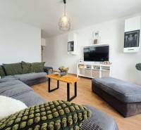 Nappali egy családi házban, fa mintázatú padlóval és kényelmes ülőgarnitúrával.