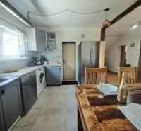 Konyha egy családi házban, fa asztallal és modern készülékekkel.