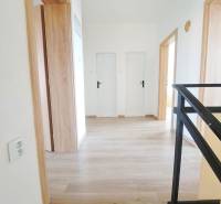 Családi ház belső tere fa dekorációjú padlóval és fehér ajtókkal.