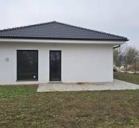 Családi ház Cíferen fehér homlokzattal és terasszal a kertben.