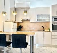 Konyha üdülő apartmanban bárpulttal, függő lámpákkal és fehér szekrénnyel.