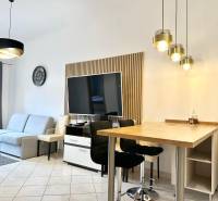 Nappali rekreációs apartman televízióval, kanapéval és bárszékekkel.