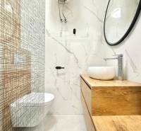 Fürdőszoba egy nyaraló apartmanban minimalista dizájnnal és hangsúlyos fa dekorációval.