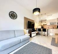 Világos nappali konyhával, kanapéval, televízióval és étkező sarokkal az üdülő apartmanban.