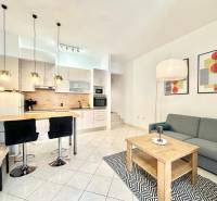 Nyaraló apartman konyhasarokkal, étkezőasztallal, kanapéval és művészeti képekkel a falon.