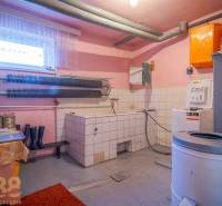 Mosókonyha családi házban mosógéppel, szárítógéppel és tárolóhellyel.