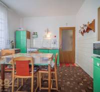 Konyha egy családi házban retro bútorokkal, étkezőasztallal és konyhai felszereléssel.