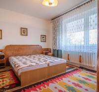 Hálószoba családi házban ággyal, szőnyegekkel és függönyökkel az ablakon.