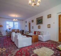 Nappali egy családi házban szőnyeggel, kanapékkal és asztallal, amely kényelmes pihenést biztosít.