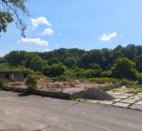 Kereskedelmi telkek a Nagykürtösi Losonci úton elhagyott épülettel, fákkal körülvéve.