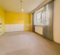 Szoba egy családi házban nagy ablakkal, sárga falakkal és függönyökkel.