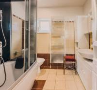 Fürdőszoba családi házban káddal, zuhanyzóval, mosdóval és radiátorral.