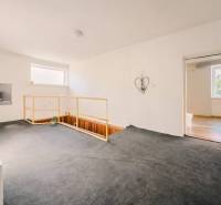 Családi ház belső tere szőnyeggel, lépcsővel és egyszerű fali dekorációval.