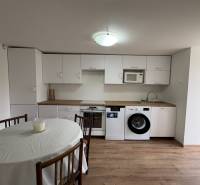 Konyha egy egyszobás lakásban fehér szekrényekkel és fa dekor padlóval.