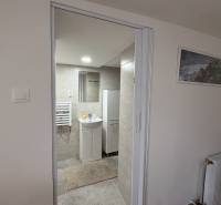 Fürdőszoba egy egyszobás lakásban mosdóval, tükörrel és radiátorral a falon.