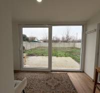 Egy szobás lakás szobája kertre néző kilátással és fa dekorációjú padlóval.