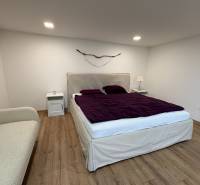 Hálószoba egy egyszobás lakásban fa dekor padlóval, ággyal és dekoratív elemmel a falon.