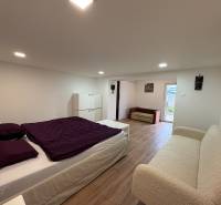 Hálószoba egy egyszobás lakásban fa dekor padlóval, egyszerű bútorokkal és dekorációkkal.