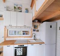 Konyha családi házban fehér szekrényekkel, fa dekorációval és színes csempével.