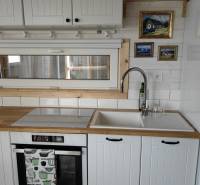 Konyhapult családi házban fehér szekrényekkel, mosogatóval és beépített sütővel.