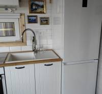 Konyha családi házban fehér konyhabútorral, hűtőszekrénnyel és művészi képekkel a falon.