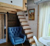 Családi ház belső tere kék fotellel, fa lépcsővel és fa dekorációjú padlóval.