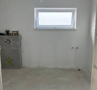 Egy családi ház üres szobája fa dekorációval és keskeny ablakkal a falon.