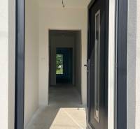 Folyosó a családi házban fehér falakkal, kilátás a kertre.