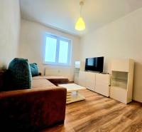 Nappali egy kétszobás lakásban kanapéval, televízióval és fa dekorációjú padlóval.