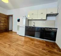 Konyha egy kétszobás lakásban, fa dekor padlóval és berendezéssel.