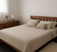 Hálószoba fa bútorokkal, ággyal és díszpárnákkal, tompa színek.