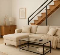 Az épület belső tere bézs kanapéval, lépcsővel és fa dekorációjú padlóval.