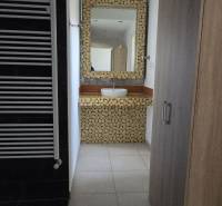 Fürdőszoba mosdóval, mozaikkal és törölközőtartóval, fa mintázatú padlóval.