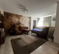 Nappali egy családi házban kanapéval, fotelekkel és falfestménnyel az ülőgarnitúra mögött.