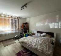 Hálószoba ággyal, edzőgépekkel, könyvespolccal és fa dekoros padlóval egy családi házban.