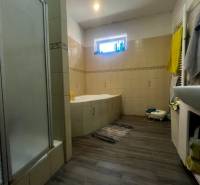 Családi ház fürdőszobája káddal, zuhanyzóval és fa padló dekorációval.