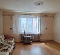 Nappali egy családi házban fa mintázatú padlóval és kanapéval.