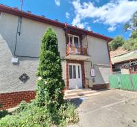 Családi ház Tachtán kapuval, terasszal, erkéllyel és zöld környezettel.