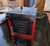 Szilárd tüzelésű kazán a családi ház pincéjében, hozzá csatlakoztatott füstgázelvezető csővel.