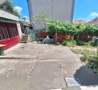 Családi ház Tachtán udvarral, betonozott területtel, zöldterülettel, kerítéssel és garázsajtókkal.