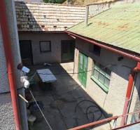 A Tachtoch családi ház udvara látható ajtókkal, asztallal és füves domboldallal.