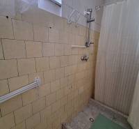 Fürdőszoba családi házban kerámia csempékkel és zuhanyfüggönnyel a zuhanyzó felett.